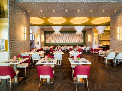 Modernes Restaurant mit roten Stühlen, weißen Tischen und dekorativer Decke.