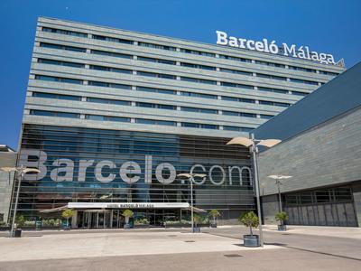 Modernes, graues Hotelgebäude mit reflektierenden Glasfenstern und blauem Himmel im Hintergrund.