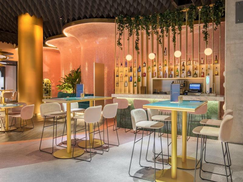 Modernes Café mit bunten Tischen, stilvollen Stühlen und warmem Beleuchtungskonzept.