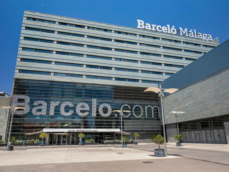 Modernes, graues Hotelgebäude mit reflektierenden Glasfenstern und blauem Himmel im Hintergrund.