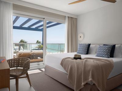 Modernes Hotelzimmer mit Doppelbett und Balkon mit Meerblick.