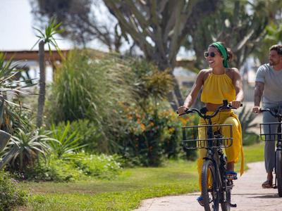 Paar fährt mit Fahrrädern auf einem sonnigen Weg in einem grünen Park.