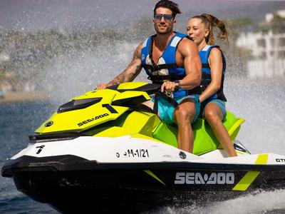 Zwei Personen auf einem gelb-schwarzen Jetski auf dem Wasser bei sonnigem Wetter.