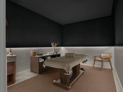 Schlichtes Behandlungszimmer mit grauen Wänden, Massageliege und Holzstuhl.