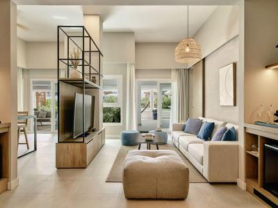 Helles Wohnzimmer mit beiger Couch, blau-grauen Kissen, moderner TV-Steckstruktur und beige Fußbank.