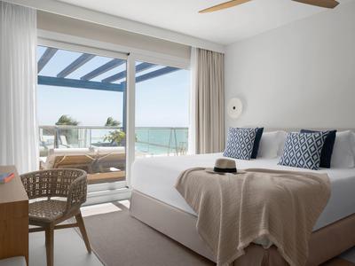 Helles Schlafzimmer mit großem Bett, Balkon mit Meerblick und moderner, heller Einrichtung.