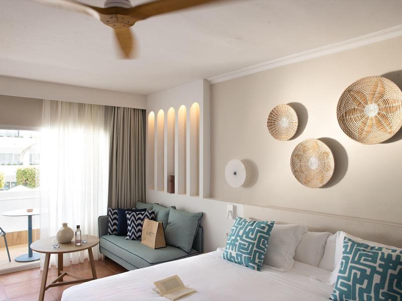 Modernes Schlafzimmer mit Doppelbett, Wanddeko aus Körben und hellen Vorhängen.