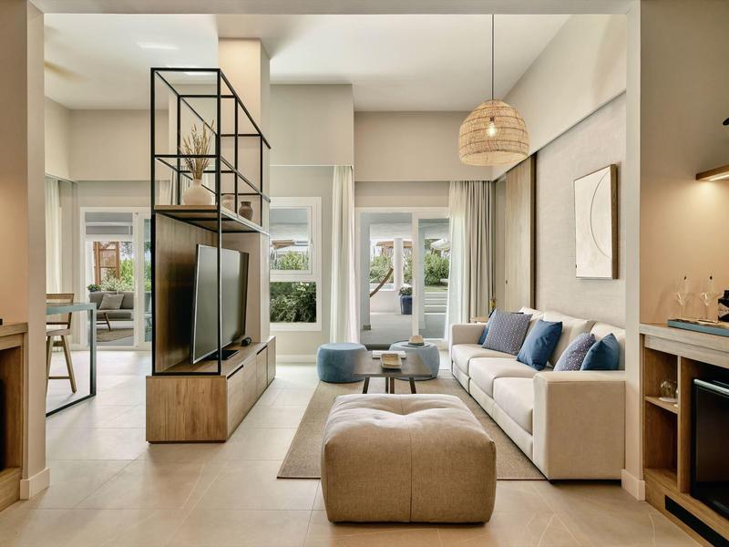 Helles Wohnzimmer mit beiger Couch, blau-grauen Kissen, moderner TV-Steckstruktur und beige Fußbank.