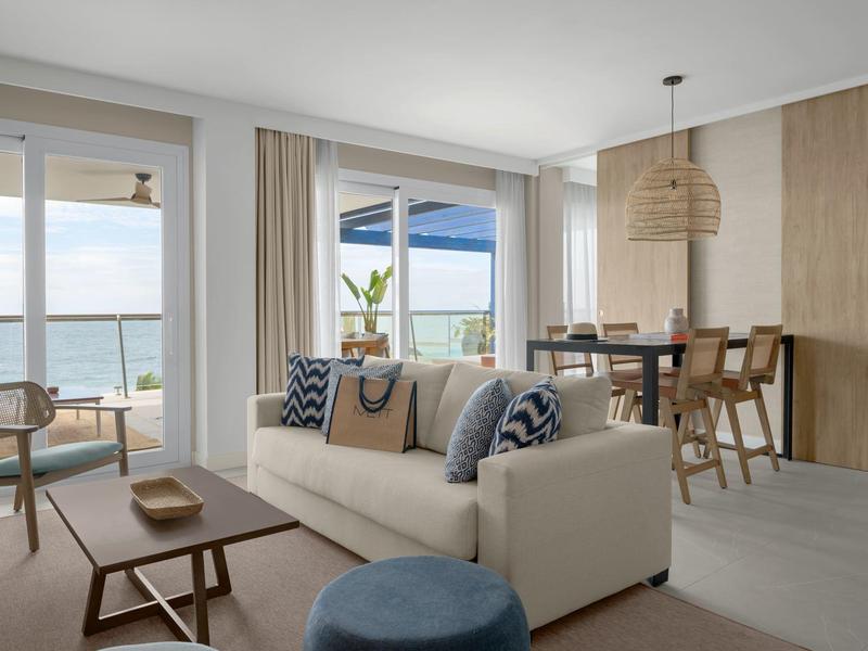 Helles Wohnzimmer mit Meerblick, Sofa, Holztisch, Esstisch und modernen, beigen Möbeln.