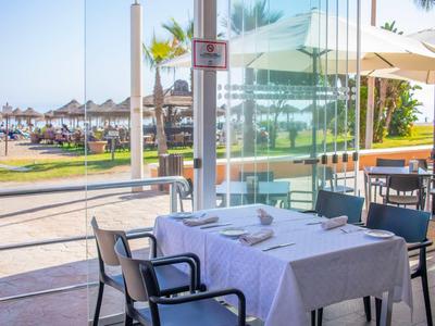 Un tavolo apparecchiato su una terrazza con vista sulla spiaggia e ombrelloni.