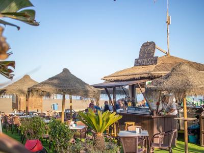 Bar all'aperto con tetti di paglia e posti a sedere in un hotel sulla spiaggia soleggiato.