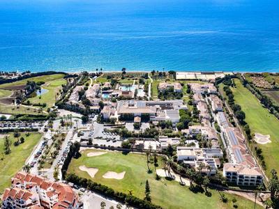 Luftaufnahme eines Strandresorts mit Hotel, Golfplatz und Blick auf das blaue Meer.