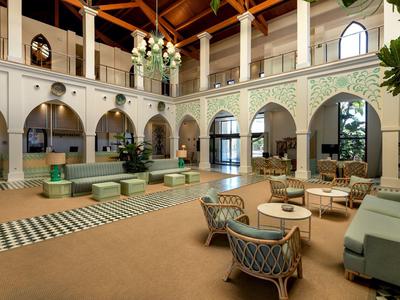 Elegante Hotellobby mit hohen Holzbalkendecken, Sitzgruppen und architektonischen Bogenfenstern.