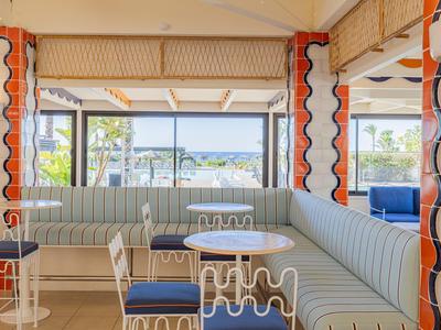 Helles Lounge-Café mit pastellfarbenen Sitzbänken und Meerblick durch große Fenster