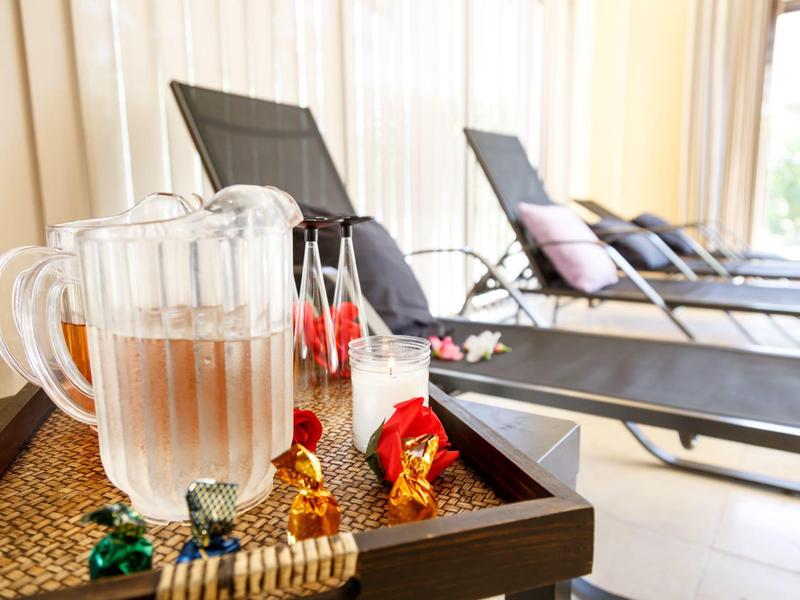 Wasserkrug und Gläser auf Tablett vor Liegestühlen in hellem Wellnessbereich