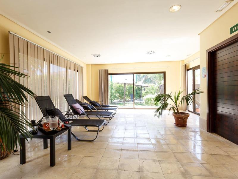 Helles Innenpool-Wellnessbereich mit Liegestühlen und großen Pflanzen.