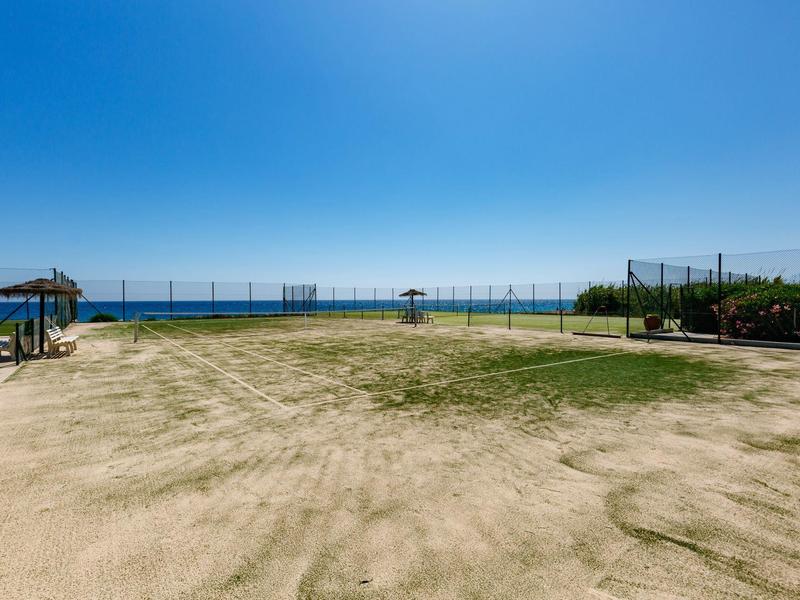 Weitläufige Sandfläche mit Blick auf das blaue Meer unter klarem Himmel.