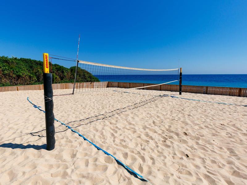 Sandvolleyballfeld mit Netz am Meer und bewölktem Himmel im Hintergrund