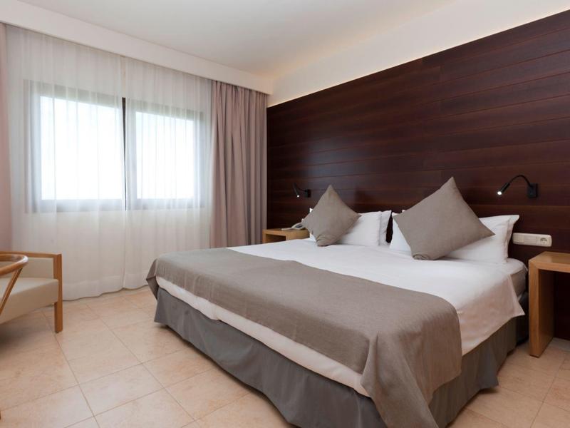 Modernes Hotelzimmer mit Doppelbett, Holzmöbeln und Fenster mit Vorhängen.