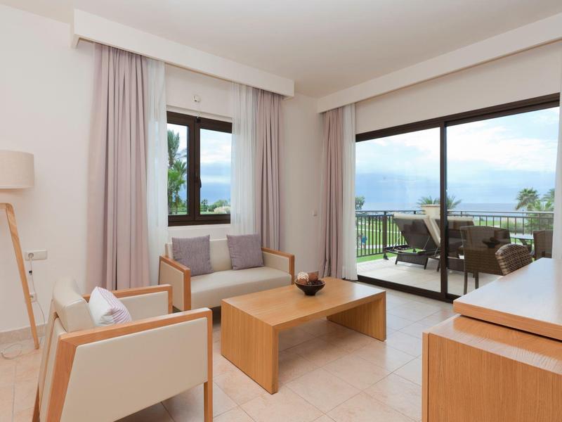 Helles Wohnzimmer mit modernen Möbeln und Blick auf Terrasse und Meer.