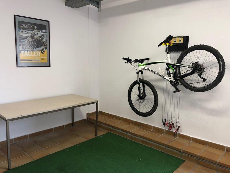 Moderner Fahrradständer an weißer Wand mit grünem Teppich und einfachem Tisch im Raum.