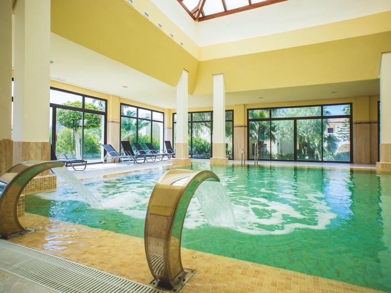 Innenpool mit Wasserdüsen und großen Fenstern, die viel Tageslicht hereinlassen.