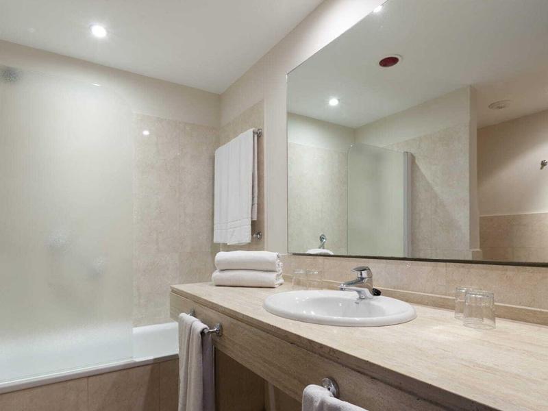 Helles modernes Badezimmer mit großer Spiegelwand, Waschbecken und Dusche mit Duschvorhang.