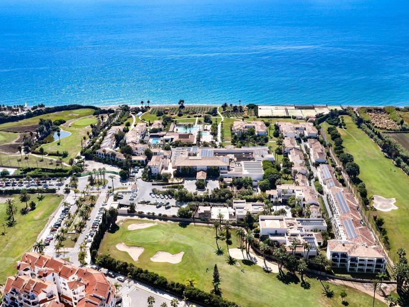 Luftaufnahme eines Strandresorts mit Hotel, Golfplatz und Blick auf das blaue Meer.