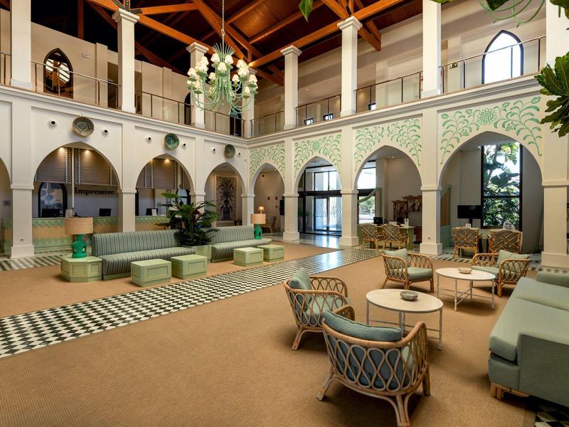 Elegante Hotellobby mit hohen Holzbalkendecken, Sitzgruppen und architektonischen Bogenfenstern.