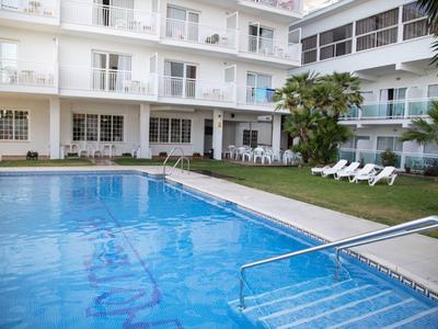 Hotelaußenbereich mit Schwimmbad, Liegestühlen und mehrstöckigem weißen Gebäude.