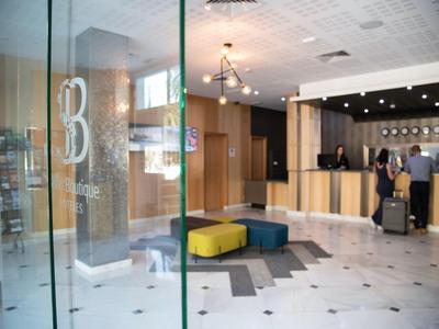 Moderne Hotellobby mit Rezeption, Sitzwürfeln und großflächigen Glaswänden.