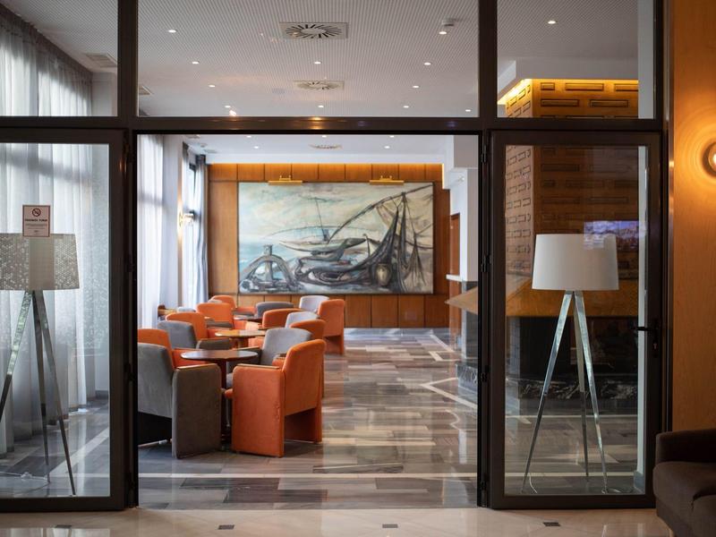 Eleganter Hotel-Lounge-Bereich mit orangen Sesseln, großer Wandkunst und modernen Lampen.