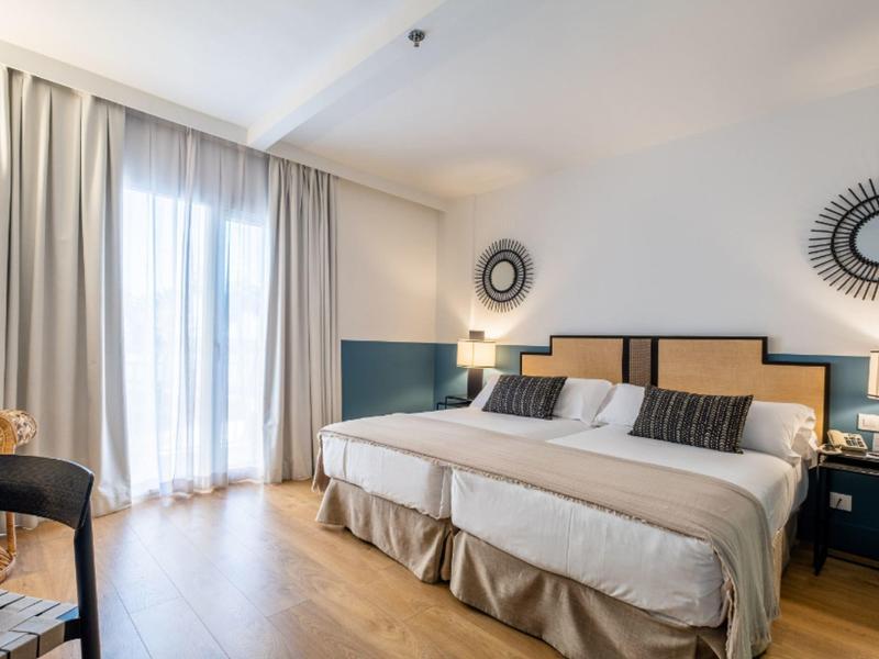 Helles Hotelzimmer mit zwei Einzelbetten, Holzfußboden und modernem Dekor.