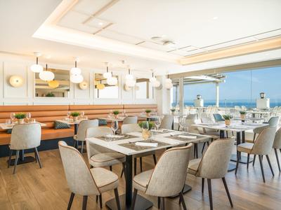 Helles Hotelrestaurant mit modernen Möbeln und Meerblick.