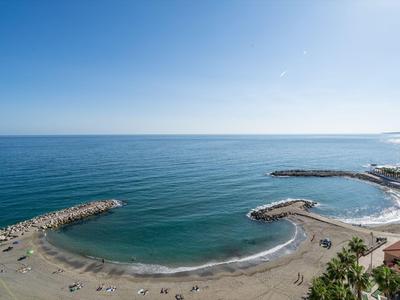 Ein ruhiger Strand mit zwei kleinen Buchten und klarem blauem Wasser unter blauem Himmel.