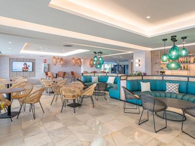 Modernes Hotelrestaurant mit runden Tischen, Holzstühlen und blauen Sofas.
