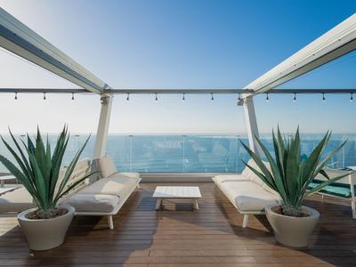 Moderne Dachterrasse mit Lounge-Möbeln und Meerblick bei klarem Himmel.