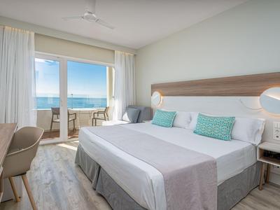 Modernes Hotelzimmer mit Doppelbett und Balkon mit Meerblick.
