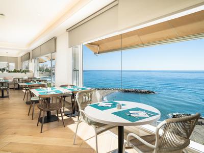 Modernes Restaurant mit großen Fenstern und Blick auf das blaue Meer.