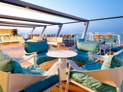 Dachterrasse mit modernen Sitzgruppen und Blick auf das Meer bei Sonnenschein.