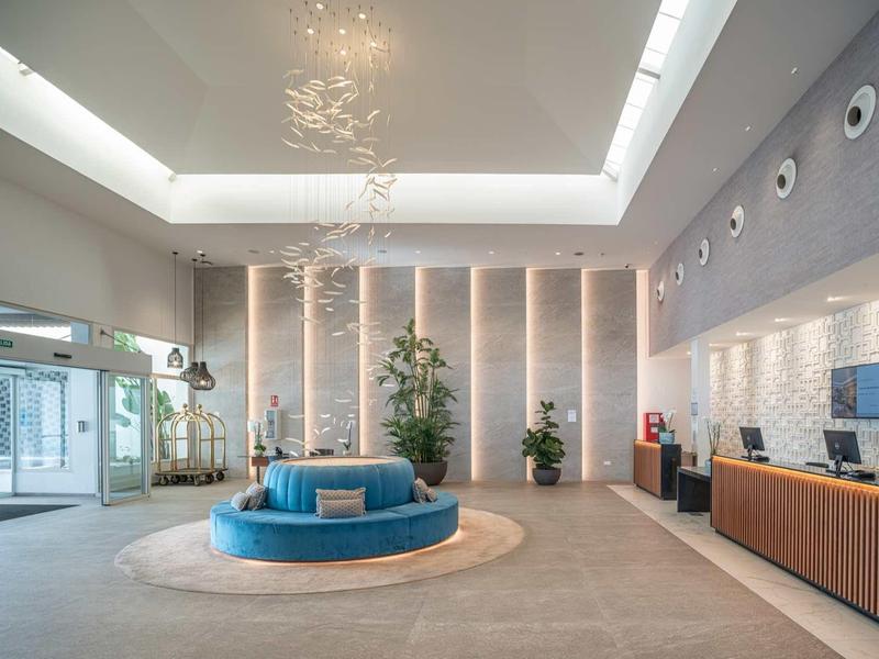 Heller, moderner Empfangsbereich mit rundem blauen Sofa, Pflanzen und Holztheke.