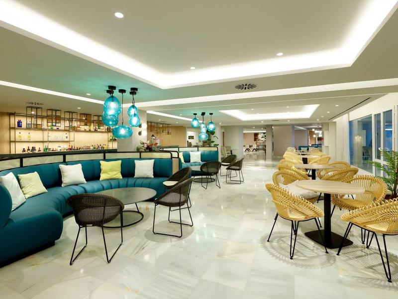 Moderne Lounge mit blauer Sofa, runden Tischen, Stühlen und großen Fenstern in hellem Raum.