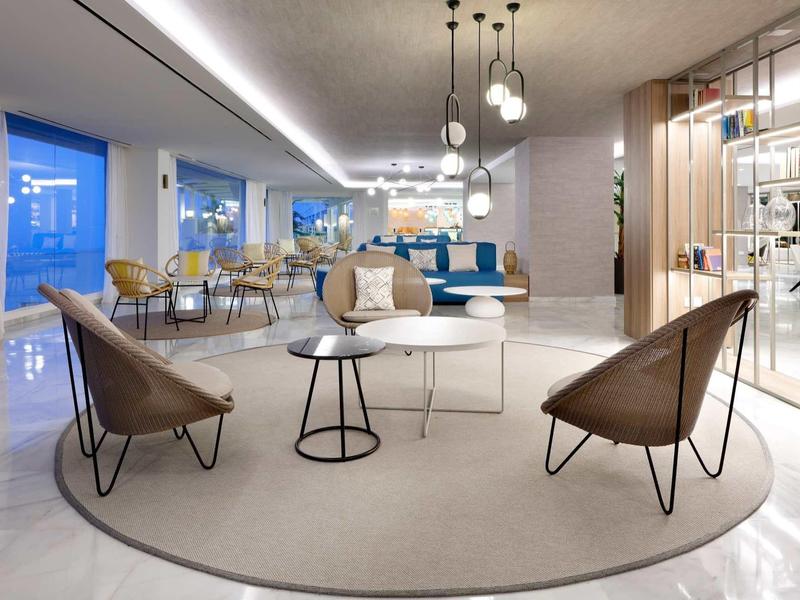 Moderner Wohnbereich mit runden Teppichen, minimalistischen Stühlen und mehreren Hängelampen.