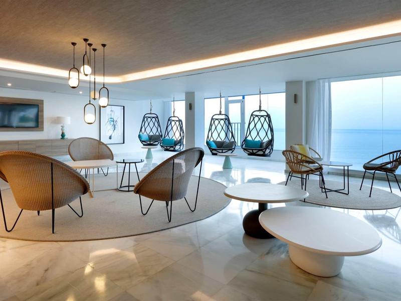 Helle, moderne Wohnzimmereinrichtung mit runden Möbeln und großen Fenstern mit Meerblick.