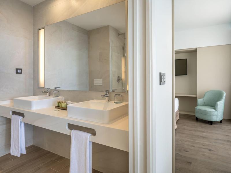 Modernes Badezimmer mit Doppelwaschbecken, großen Spiegeln und weißem Waschtisch neben hellem Wohnzimmer.