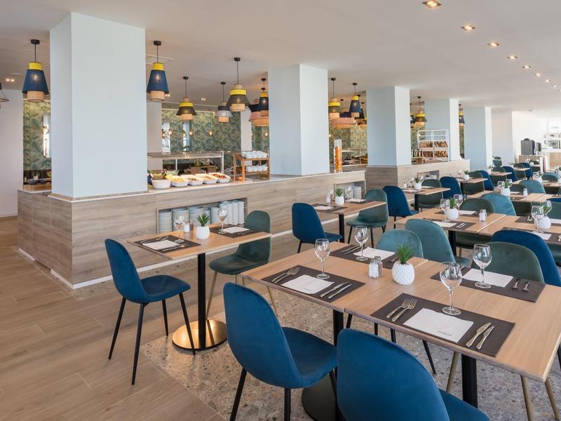 Großes, modernes Restaurant mit Holzboden, blauen Stühlen, hellen Wänden und vielen Tischen.