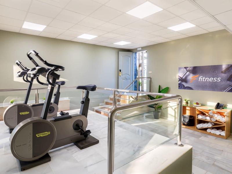 Heller Fitnessraum mit zwei Trainingsrädern, Fenster und Fitness-Poster an der Wand.