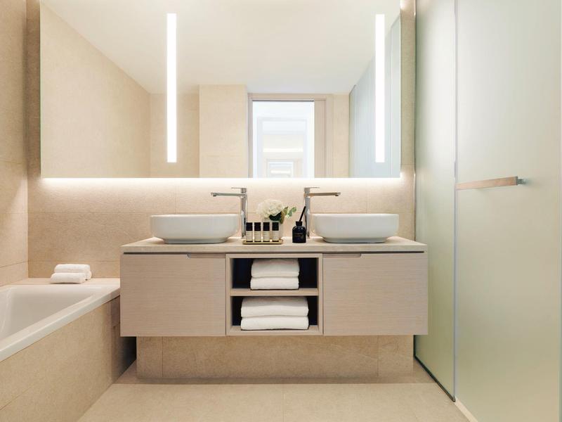 Helles Badezimmer mit doppeltem Waschbecken, freistehender Badewanne und großem Spiegel.