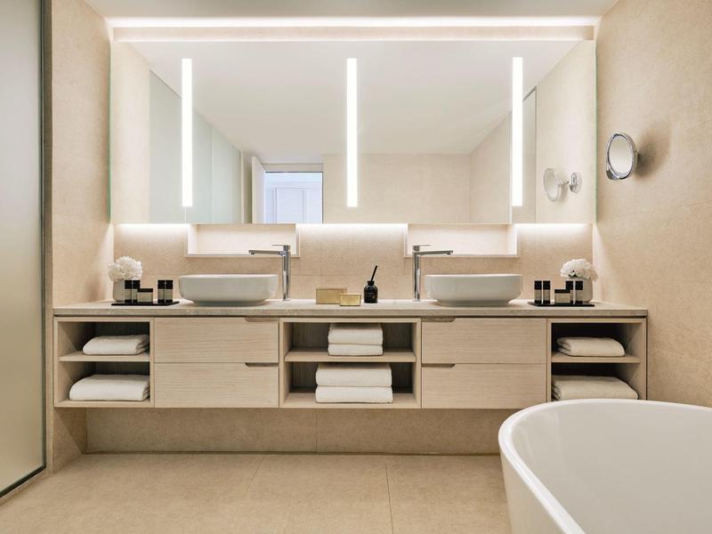 Modernes Badezimmer mit zwei Waschbecken, großen Spiegeln, Beleuchtung und freistehender Badewanne.