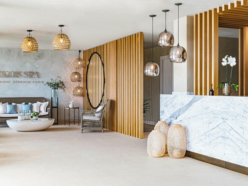 Heller Empfangsbereich mit Marmor-Tresen, hängenden Lampen, Holzpaneelen und gemütlicher Sitzgruppe.